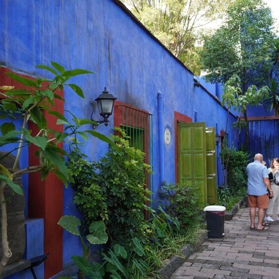 A blue building with a green door and a trash can. 2