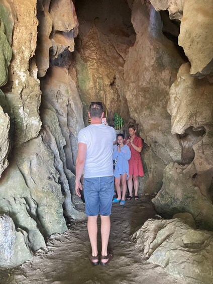 A person walking through a cave with rocky walls and a narrow passage. 1