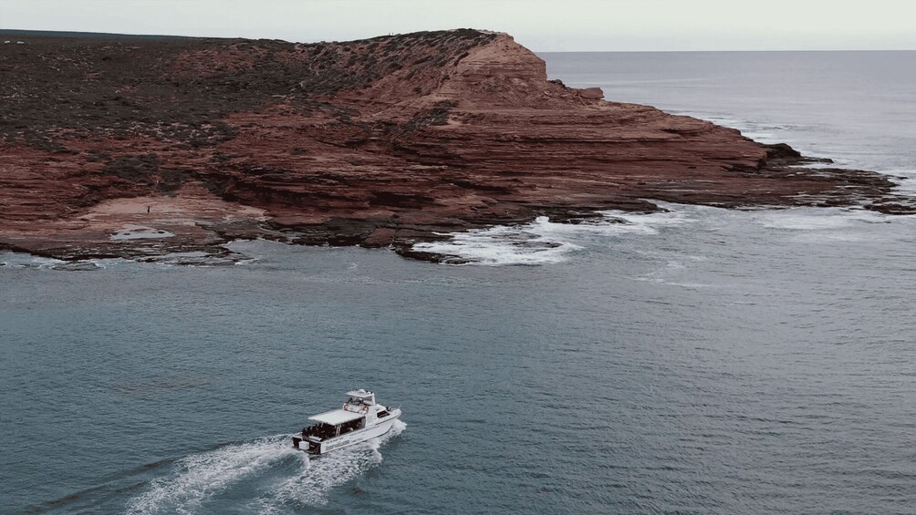 A boat on calm waters near a rocky coastline. 2