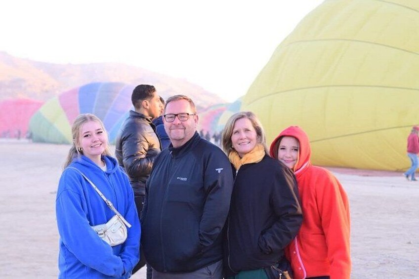 A group of people standing in front of large colorful balloons. 5