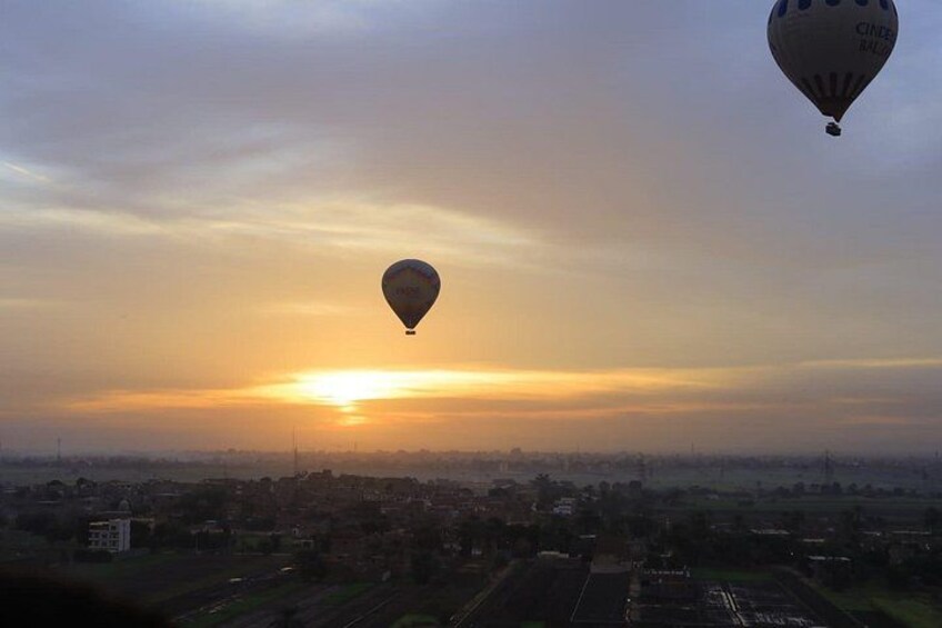 A hot air balloon flying over a cityscape during sunset. 2