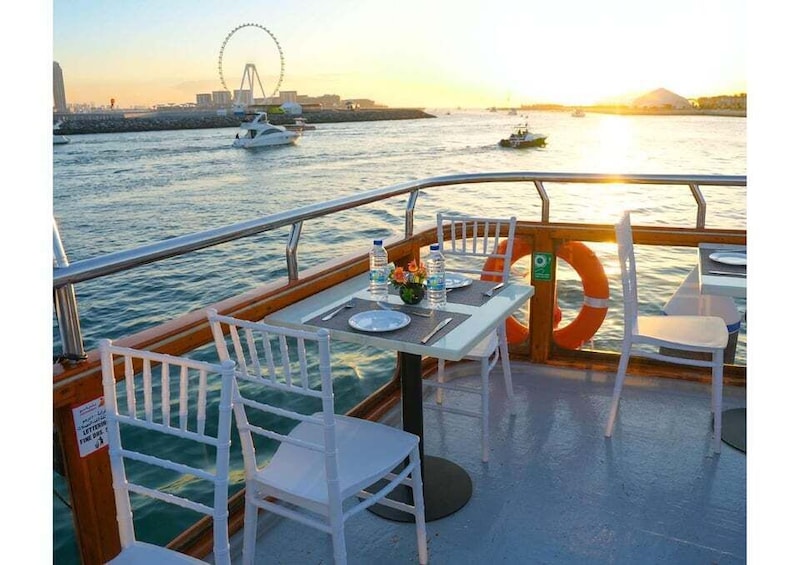 A boat deck with a table set for two, a life ring, and a Ferris wheel in the background. 1