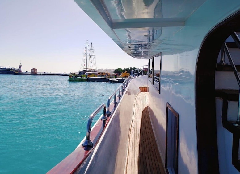 A boat's deck with a view of the water and distant buildings. 2