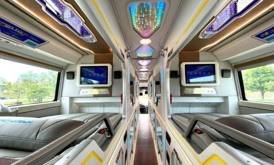 A train interior with seats, overhead compartments, and digital screens. 3