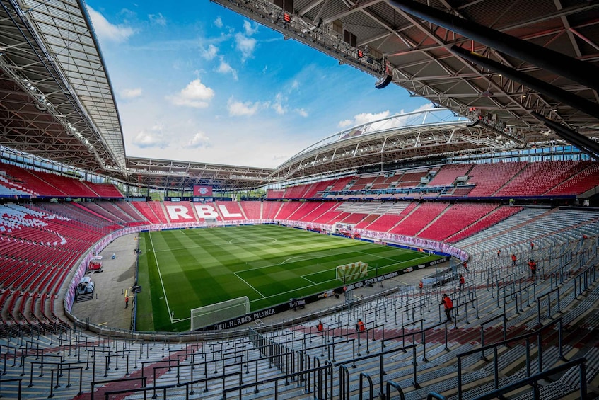 A large stadium with red seats and a green field. 1