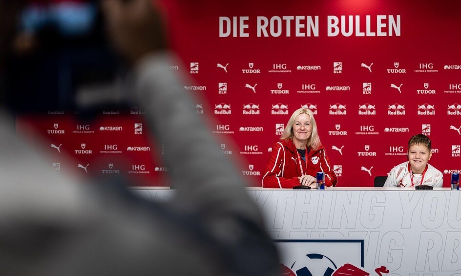 Two people at a press conference with a backdrop featuring logos of sponsors like Red Bull, IHG, and Puma. 4