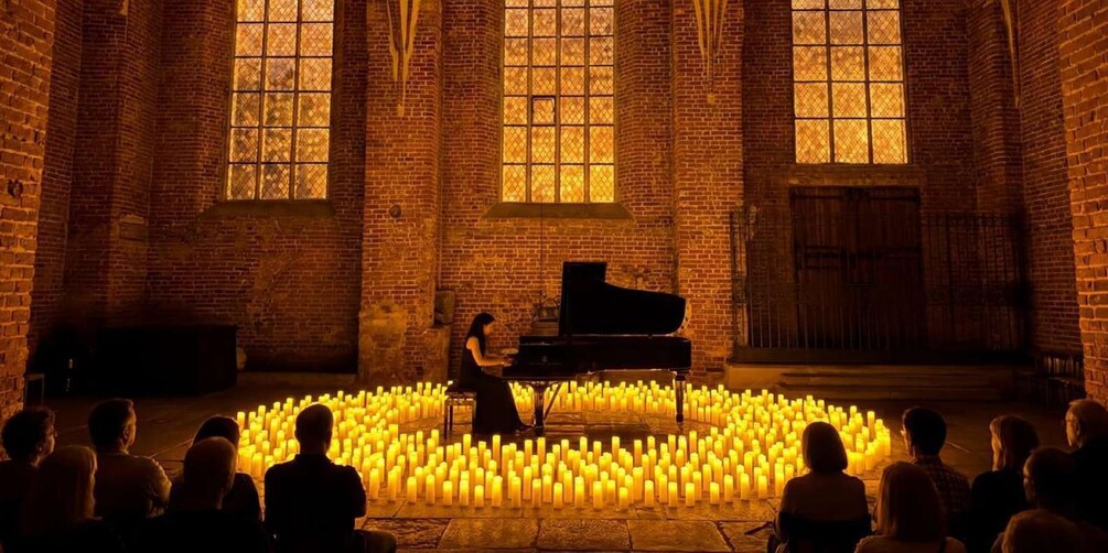 A pianist performing in a brick-walled room surrounded by candles. 3