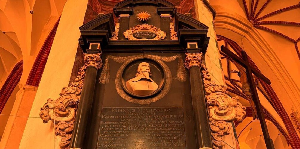 A statue of a historical figure with an inscription, surrounded by ornate architectural details. 2