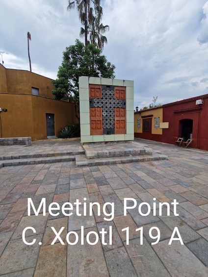 A courtyard with a central structure featuring a cross design, surrounded by buildings with traditional architecture. 2