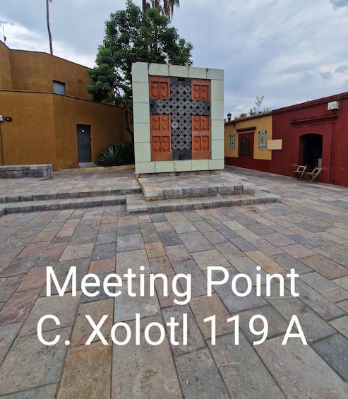 A courtyard with a central decorative structure, stone steps, and buildings with distinct architectural styles. 3