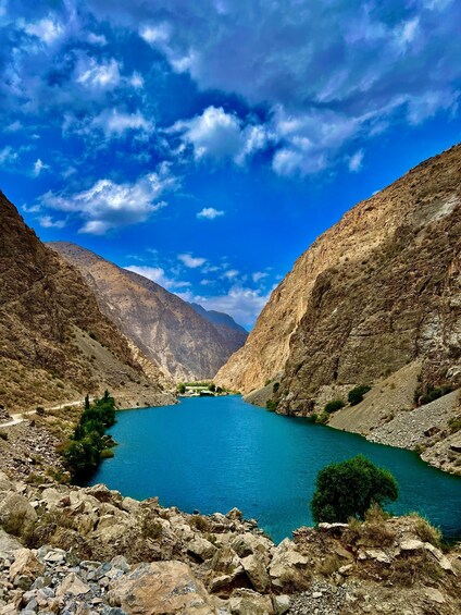 A turquoise lake surrounded by rocky mountains under a partly cloudy sky. 5