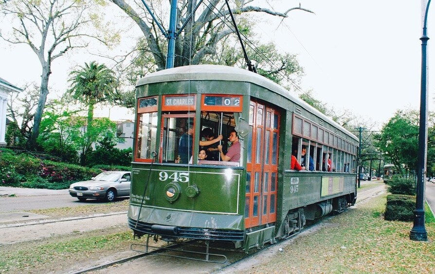 A vintage tram numbered 945 on tracks, with passengers visible through the windows. 5