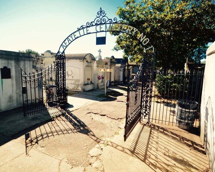 A cemetery entrance with wrought iron gates and a sign above them. 1