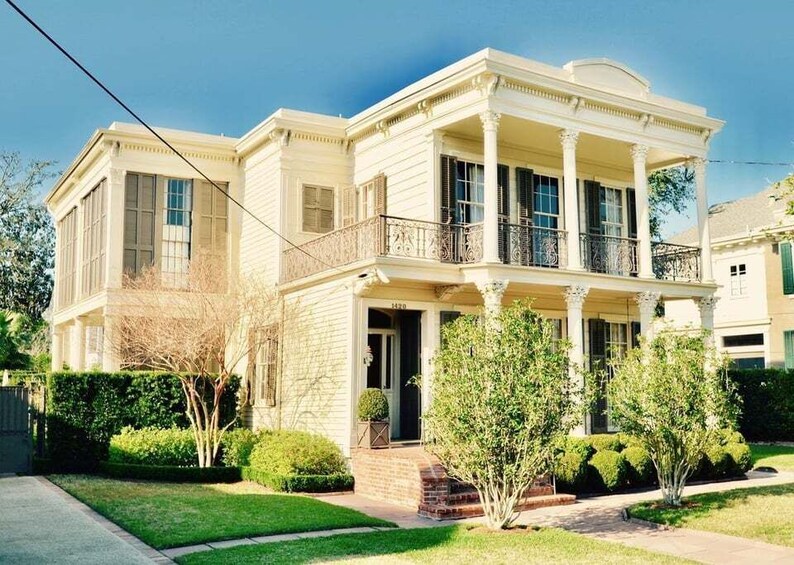 A large, two-story house with a balcony and columns. 2