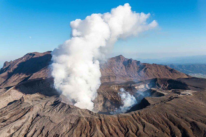 A volcanic landscape with a prominent plume of smoke rising from a crater. 5