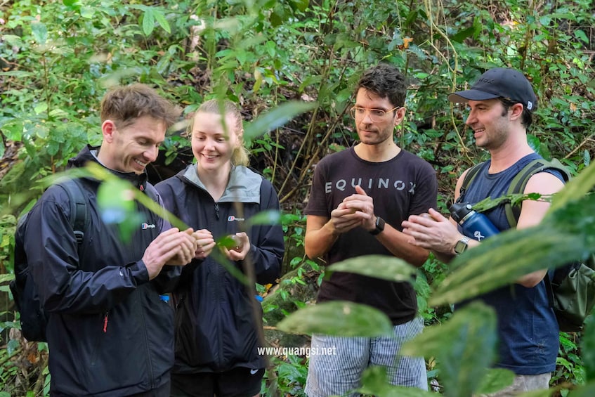 Four people in a forested area, examining a green object. 2