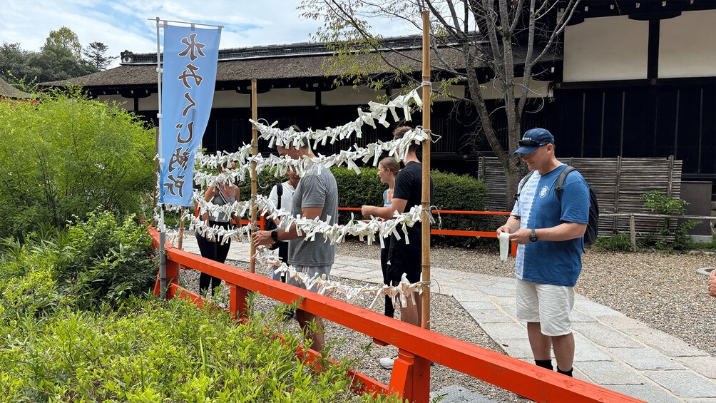 A traditional Japanese torii gate with a blue banner, surrounded by greenery and a building in the background. 5