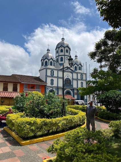 A church with domes and crosses, surrounded by well-maintained gardens and a paved walkway. 3