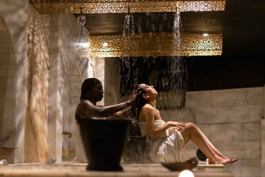 A woman sitting in a bathtub with water flowing over her head. 1