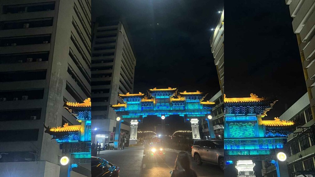 A brightly lit traditional gate with blue and yellow lights, surrounded by modern buildings. 3