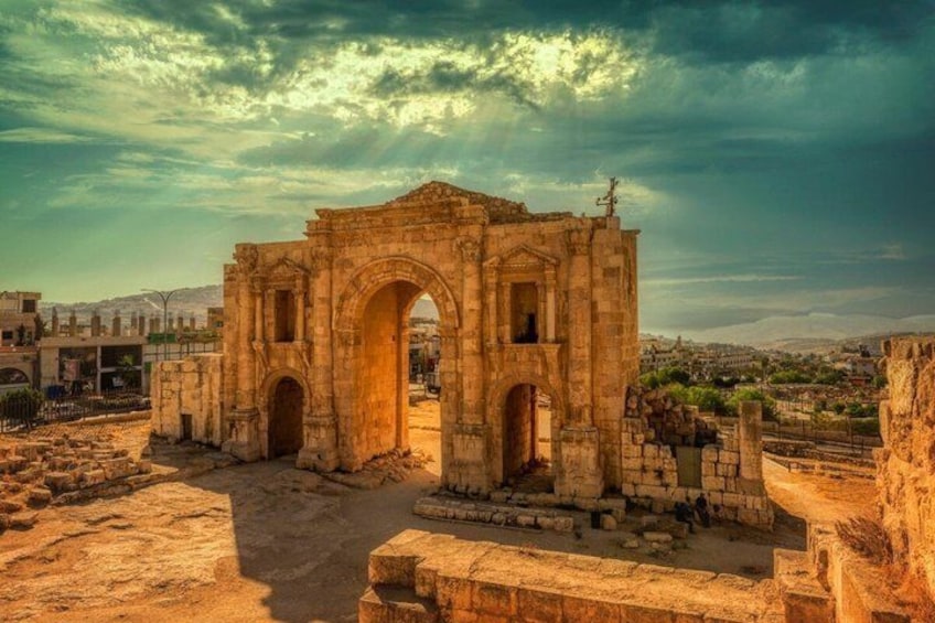 Ancient ruins with an arched gateway, surrounded by stone walls and a clear sky. 1