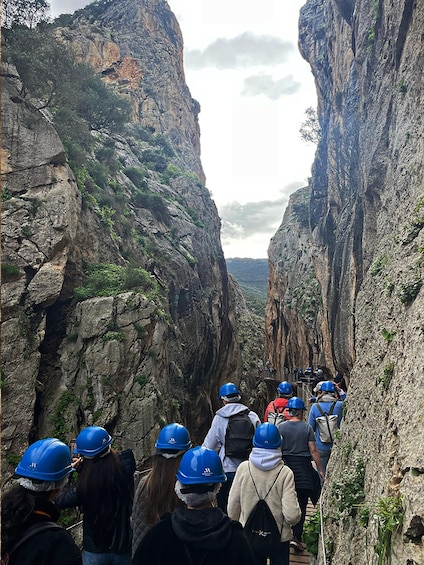 A group of people wearing helmets and backpacks walking through a narrow canyon with steep rock walls. 3