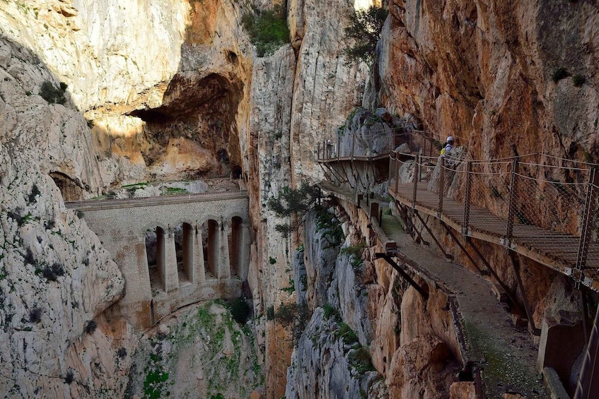 A rocky canyon with a wooden walkway and ancient ruins. 4