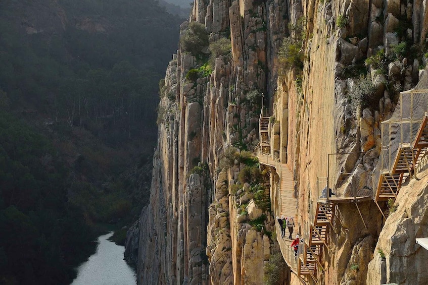 A narrow wooden walkway along a steep cliffside with a river below. 5