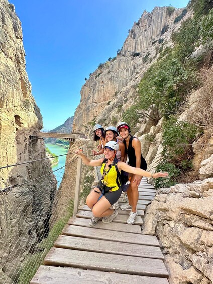 A group of people on a wooden staircase with a canyon and river in the background. 2