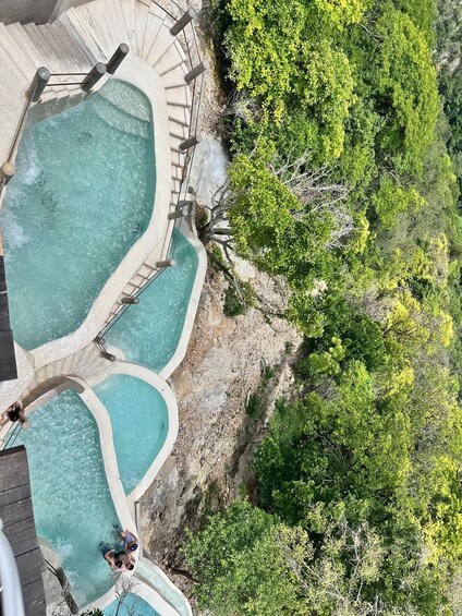 A hot spring area with multiple pools surrounded by lush greenery. 2