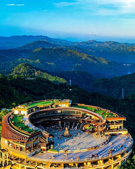 A large amphitheater with a circular design, surrounded by lush green hills and a clear sky. 4