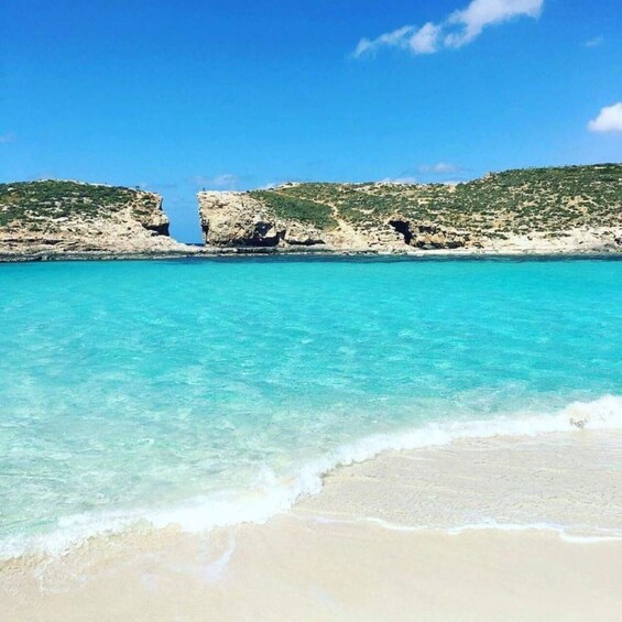 A beach with clear turquoise water, sandy shore, and rocky cliffs. 4