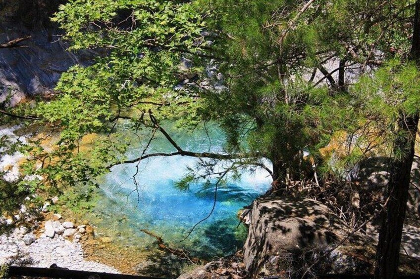 A clear blue lake surrounded by trees and rocky terrain. 1