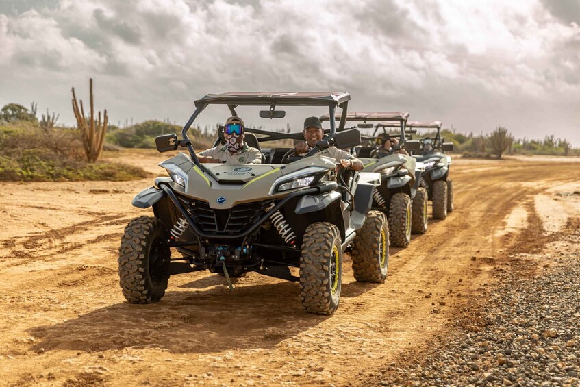 A convoy of off-road vehicles on a dirt road in a desert landscape. 4