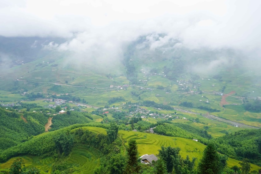 A lush green valley with terraced fields and scattered houses, surrounded by dense forests and mist. 4
