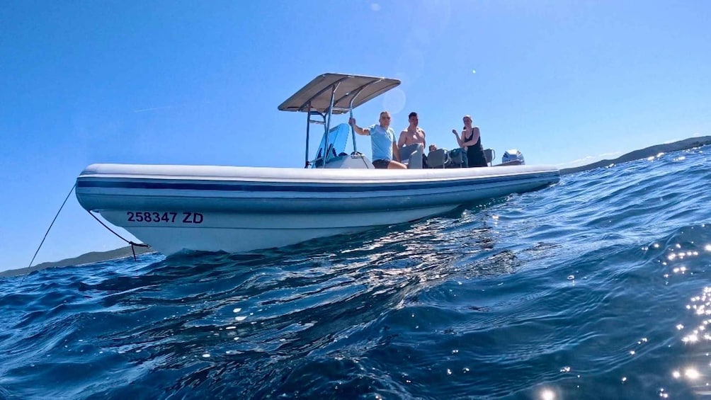 A motorboat with three people on board, sailing on a clear blue sea. 5