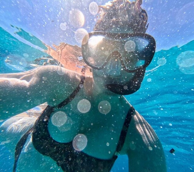 A person snorkeling underwater with bubbles and sunlight filtering through the water. 4