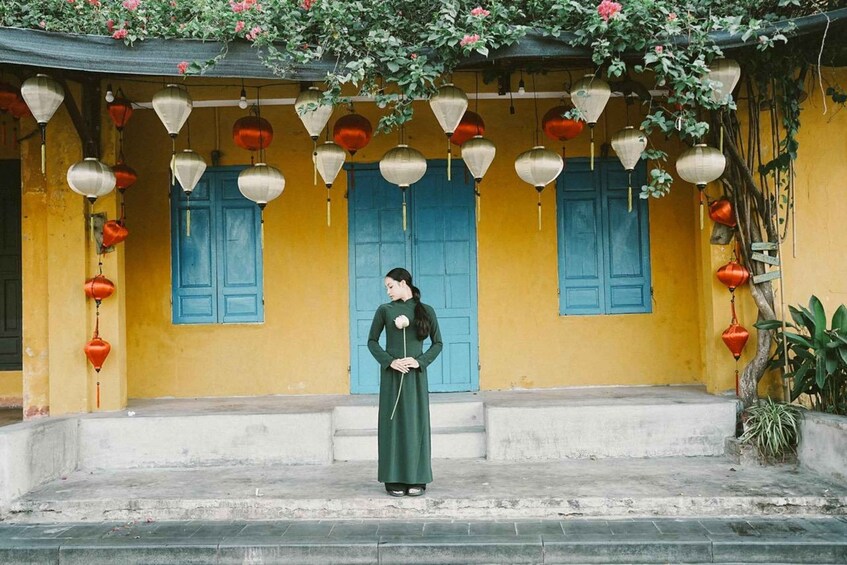 A person standing in front of a yellow building with blue doors and hanging lanterns. 4