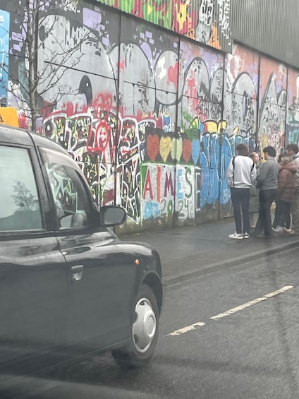 A car parked on a street with a colorful graffiti-covered wall in the background. 2
