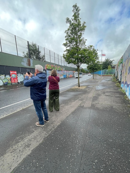 Two people taking a photo of a street with graffiti on the walls. 4