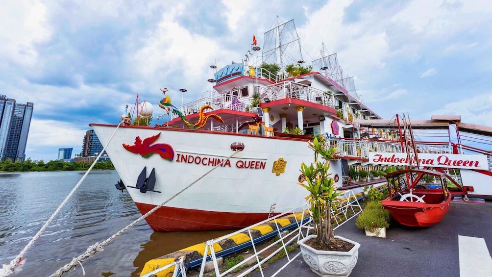 A boat named 'Indochina Queen' docked at a pier with a city skyline in the background. 2