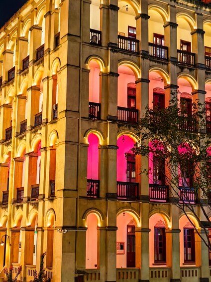 A building with multiple arches and balconies, illuminated with warm lighting. 2