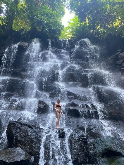 A waterfall with a person standing on rocks. 5