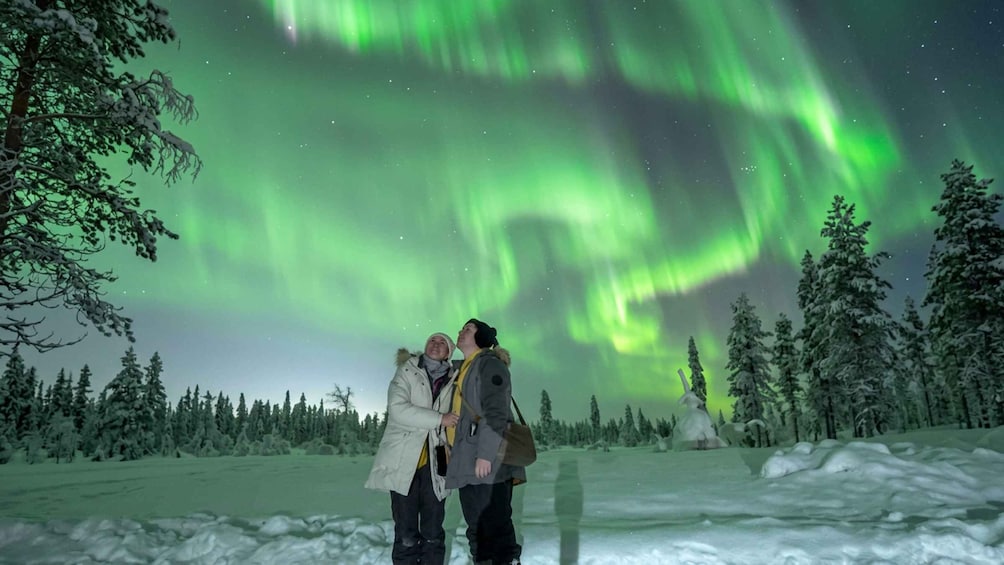 Paisaje nevado con gente observando las auroras boreales. 1