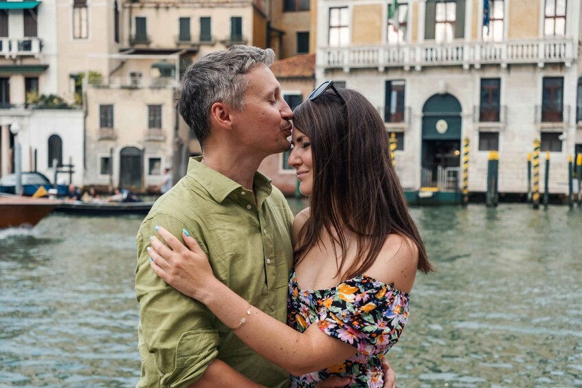 A couple embracing by a canal with historic buildings in the background. 3