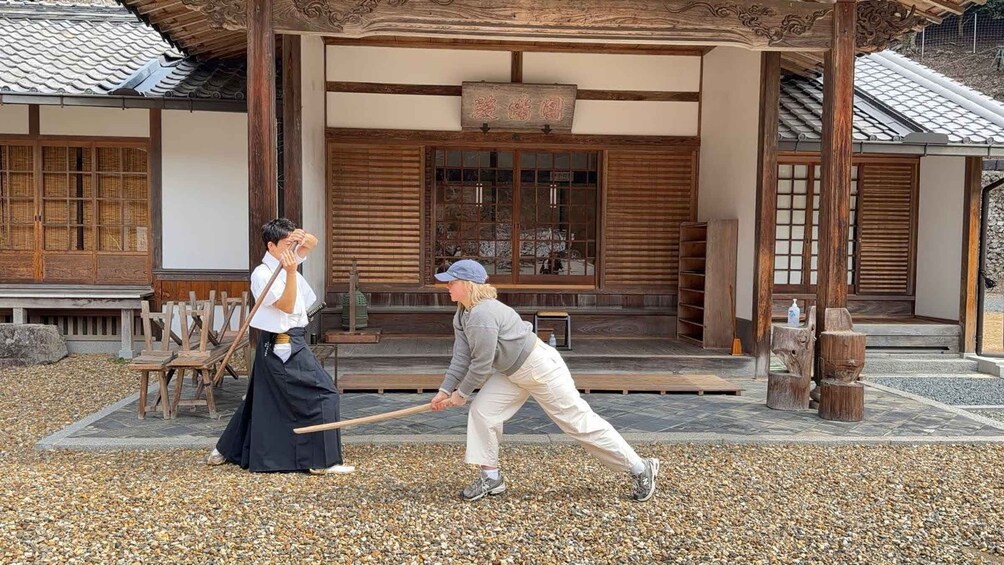 Two people playing a traditional game in front of a traditional Japanese building. 1