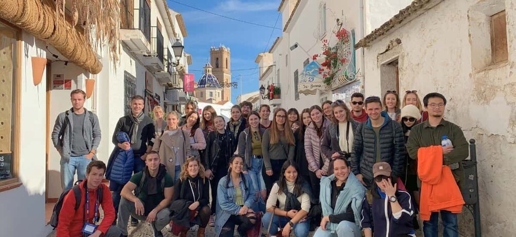 A group of people posing in a narrow street with buildings on either side. 5