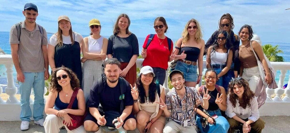 A group of people posing on a balcony with a view of the ocean. 2