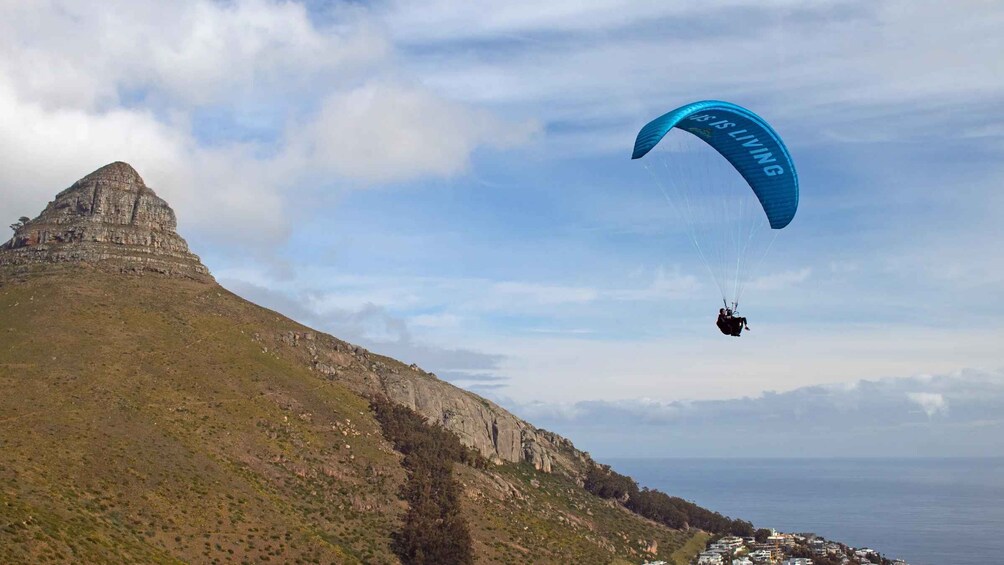A paraglider flying over a mountainous landscape with a clear sky. 3