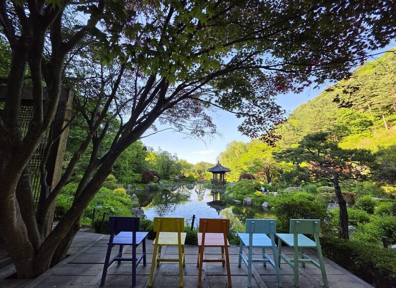 A serene garden with a pond, a gazebo, and colorful chairs. 3